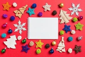 vue de dessus du cahier sur fond rouge fait de décorations de vacances et de jouets. concept d'ornement de noël photo