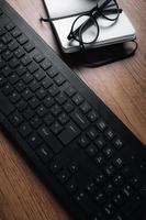 vue de dessus du bureau vintage en bois concentré sur un ordinateur portable avec bloc-notes, smartphone et lunettes. lieu de travail. travail à domicile. bureau. photo