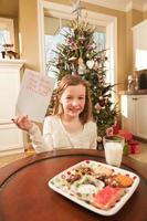 Enfant offrant des cookies et écrivant la liste de souhaits de Noël au père Noël