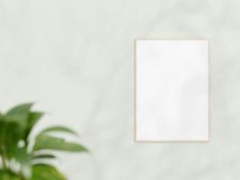 maquette de cadre en bois vertical sur mur blanc. maquette d'affiche. cadre épuré, moderne et minimaliste. cadre vide intérieur intérieur, afficher le texte ou le produit. maquette de cadre avec ombre et plante. rendu 3d. photo