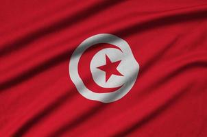 le drapeau tunisien est représenté sur un tissu de sport avec de nombreux plis. bannière de l'équipe sportive photo