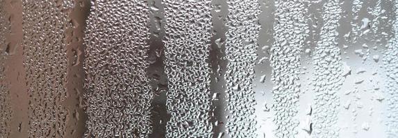 la texture d'un verre embué avec beaucoup de gouttes et de flux de condensation. image de fond photo