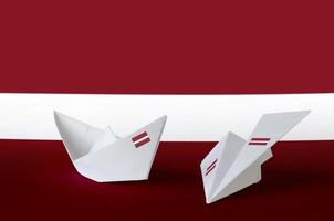 drapeau de la lettonie représenté sur un avion et un bateau en papier origami. concept d'art fait à la main photo