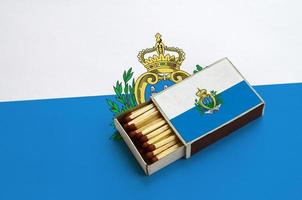 le drapeau de saint-marin est affiché dans une boîte d'allumettes ouverte, qui est remplie d'allumettes et repose sur un grand drapeau photo