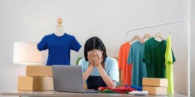 femme vendeuse PME propriétaire d'un magasin de détail travaille dur s'inquiète du stress dans les mauvaises nouvelles sur un ordinateur portable au bureau à domicile. problème d'emploi de tailleur de crise des personnes asiatiques se sentent fatigués et bouleversés par la perte d'argent en espèces ou la dette de prêt. photo