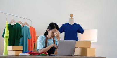 femme vendeuse PME propriétaire d'un magasin de détail travaille dur s'inquiète du stress dans les mauvaises nouvelles sur un ordinateur portable au bureau à domicile. problème d'emploi de tailleur de crise des personnes asiatiques se sentent fatigués et bouleversés par la perte d'argent en espèces ou la dette de prêt. photo