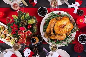 dinde au four. dîner de Noël. la table de noël est servie avec une dinde, décorée de guirlandes lumineuses et de bougies. poulet frit, table. dîner de famille. vue de dessus photo