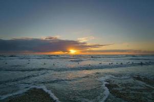 coucher de soleil sur la plage au danemark. vagues roulant sur le sable. marcher sur la côte photo