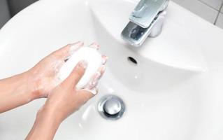 la femme utilise du savon et se lave les mains sous le robinet d'eau. photo