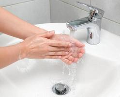la femme utilise du savon et se lave les mains sous le robinet d'eau. photo