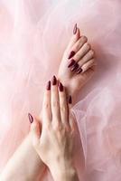 mains d'une jeune femme avec une manucure rouge foncé sur les ongles photo