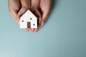 mains adultes et enfants tenant ensemble une petite maison en bois. photo