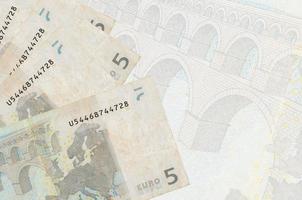 5 billets en euros sont empilés sur fond de gros billets semi-transparents. arrière-plan abstrait des affaires photo