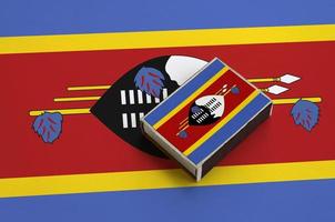 le drapeau du swaziland est représenté sur une boîte d'allumettes posée sur un grand drapeau photo