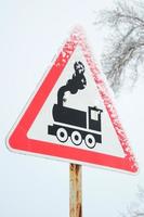 passage à niveau sans barrière. un panneau routier représentant une vieille locomotive noire, situé dans un triangle rouge photo