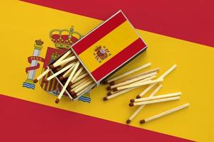 le drapeau espagnol est affiché sur une boîte d'allumettes ouverte, d'où tombent plusieurs allumettes et se trouve sur un grand drapeau photo