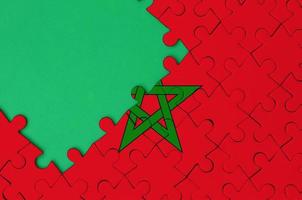 le drapeau du maroc est représenté sur un puzzle terminé avec un espace de copie vert gratuit sur le côté gauche photo