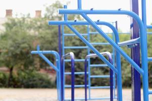 bars sportifs en bleu sur le fond d'un terrain de sport de rue pour l'entraînement en athlétisme. équipement de gym athlétique en plein air. photo macro avec mise au point sélective et arrière-plan extrêmement flou