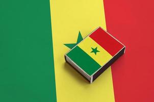 le drapeau du sénégal est représenté sur une boîte d'allumettes posée sur un grand drapeau photo