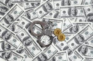 les menottes de la police et les bitcoins reposent sur un grand nombre de billets d'un dollar. le concept de problèmes avec la loi lors des opérations illégales d'extraction de crypto-monnaie et de bitcoin photo