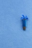 carte mémoire flash usb bleu brillant avec un arc bleu se trouve sur une couverture de tissu polaire bleu clair doux et poilu. conception de cadeau féminin classique pour une carte mémoire photo
