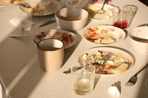 vider les assiettes sales avec des cuillères et des fourchettes sur la table après le repas. concept de fin de banquet. vaisselle non lavée photo