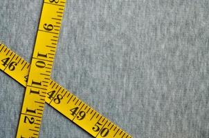 ruban à mesurer jaune se trouve sur un tricot gris photo