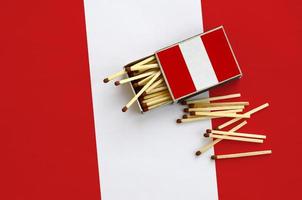 le drapeau du pérou est affiché sur une boîte d'allumettes ouverte, d'où tombent plusieurs allumettes et repose sur un grand drapeau photo