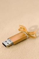 carte mémoire flash usb orange avec un arc bleu se trouve sur une couverture de tissu polaire orange clair doux et poilu. conception de cadeau féminin classique pour une carte mémoire photo