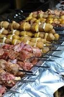 la viande crue et les pommes de terre sont plantées sur des brochettes en métal. le processus de cuisson des shish kebabs. nourriture de camp russe et ukrainienne photo