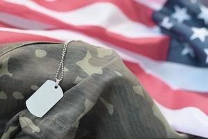 Perles militaires argentées avec étiquette de chien sur le drapeau en tissu des États-Unis et uniforme de camouflage photo