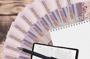 Éventail de billets de 500 roubles russes et bloc-notes avec carnet de contacts et stylo noir. concept de planification financière et de stratégie d'entreprise photo