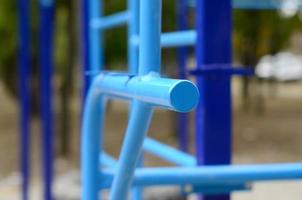 bars sportifs en bleu sur le fond d'un terrain de sport de rue pour l'entraînement en athlétisme. équipement de gym athlétique en plein air. photo macro avec mise au point sélective et arrière-plan extrêmement flou