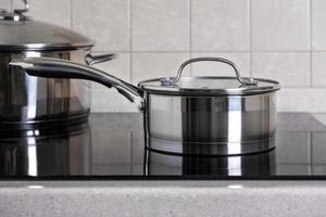 louche et grande casserole se tiennent sur une cuisinière moderne avec une plaque vitrocéramique photo
