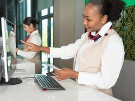 femme officier africaine travaillant au comptoir de service d'enregistrement de la compagnie aérienne photo