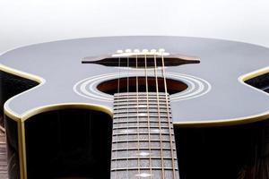 guitare acoustique noire sur table en bois et fond blanc. photo