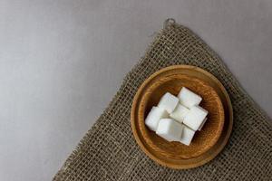 cubes de sucre dans des assiettes en bois sur un sac sur la table de la cuisine. vue de dessus. avec espace de copie photo