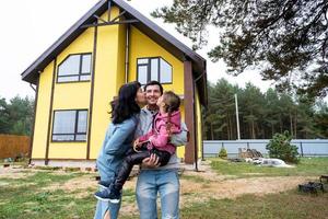 famille heureuse dans la cour d'une maison inachevée - achat d'un chalet, hypothèque, prêt, déménagement, construction photo