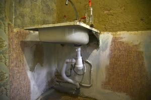 un vieil évier de cuisine en fer avec un robinet dans l'ancienne cuisine. rénovation dans la cuisine et crépis frais. lavabo avec siphon sanitaire. photo