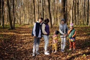 mère avec quatre enfants en loisirs familiaux à l'activité d'automne en forêt. photo