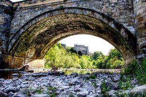 À la recherche sous un pont de pierre avec le château de Richmond en arrière-plan, North Yorkshire photo
