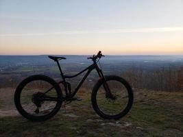 un vélo de montagne silhouetté avec un coucher de soleil et un arrière-plan de terres agricoles photo