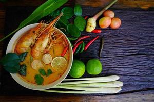 tom yum kung dans une tasse sur un plancher en bois, tom yum kung est aussi le plat national de la thaïlande. et est un aliment célèbre dans le monde entier. photo