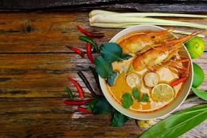 tom yum kung dans une tasse sur un plancher en bois, tom yum kung est aussi le plat national de la thaïlande. et est un aliment célèbre dans le monde entier. photo