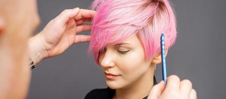 coiffeur vérifiant la coiffure rose de la femme. photo