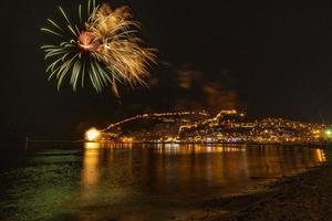 magnifique reflet des feux d'artifice nocturnes sur la mer et la vue sur la mer de la ville photo