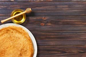 pile de crêpes savoureuses avec du miel en pot sur la vue de dessus de fond en bois avec espace de copie. vue de dessus avec espace de copie photo