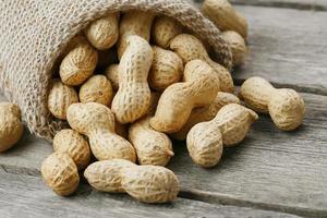 cacahuètes dans un sac de toile de jute miniature sur une vieille surface en bois grise photo