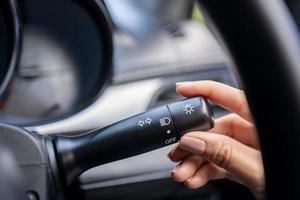 femme allumant le commutateur de signal gauche, gros plan de sa main. détails de l'intérieur de la voiture. photo