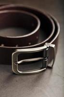 ceinture marron pour hommes à la mode en cuir véritable avec une boucle en métal clair sur fond sombre. cuir véritable, fait main photo